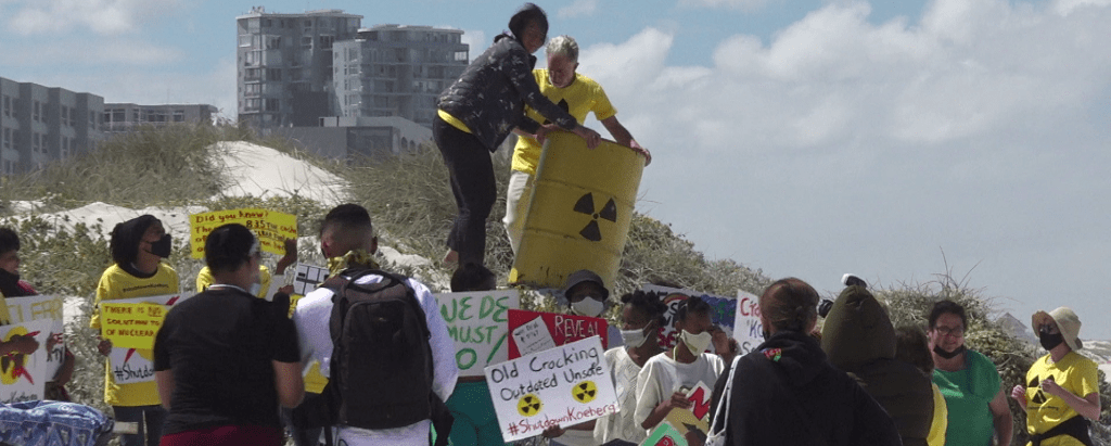Demonstrators on beach holding posters